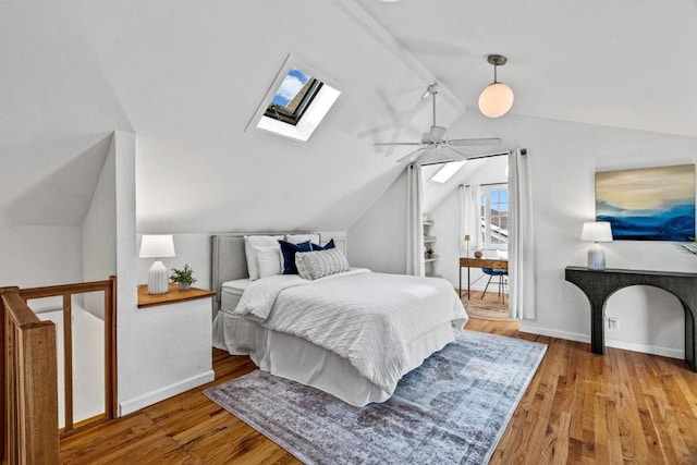 bedroom featuring ceiling fan, hardwood / wood-style floors, and vaulted ceiling with skylight