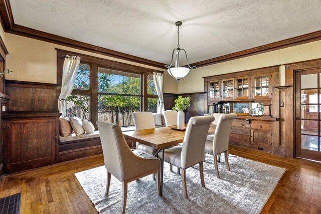 dining room with a textured ceiling, crown molding, and dark hardwood / wood-style flooring