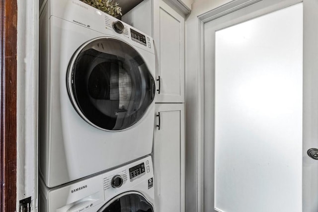 clothes washing area with stacked washer and dryer and cabinets