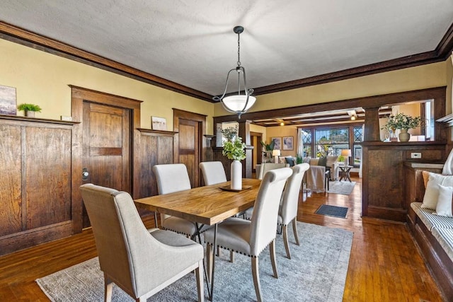 dining area featuring dark wood-type flooring, a textured ceiling, and crown molding