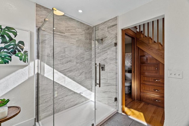 bathroom featuring a shower with door, tile patterned flooring, and toilet