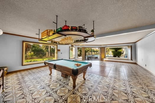 rec room featuring pool table, ornamental molding, and a textured ceiling