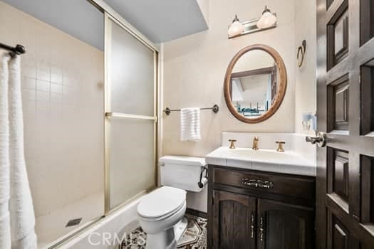 bathroom featuring toilet, an enclosed shower, and vanity