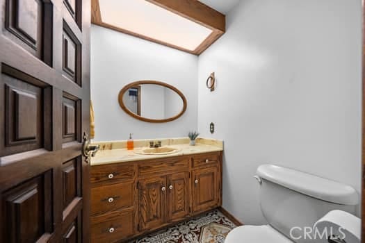 bathroom featuring beamed ceiling, tile patterned floors, vanity, and toilet