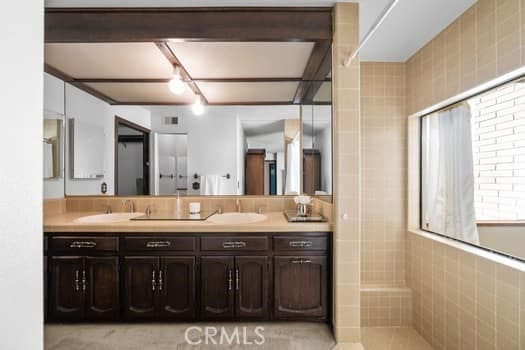 bathroom with vanity, walk in shower, and tile walls