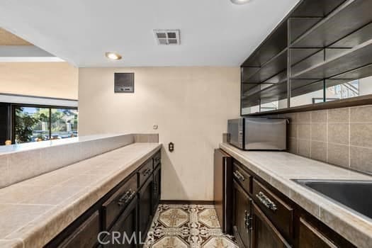 kitchen with light tile patterned floors, tile countertops, and dark brown cabinets