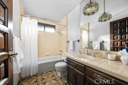 full bathroom featuring vanity, shower / bath combo with shower curtain, and toilet