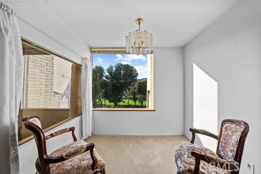 sitting room with an inviting chandelier, a wealth of natural light, and light colored carpet