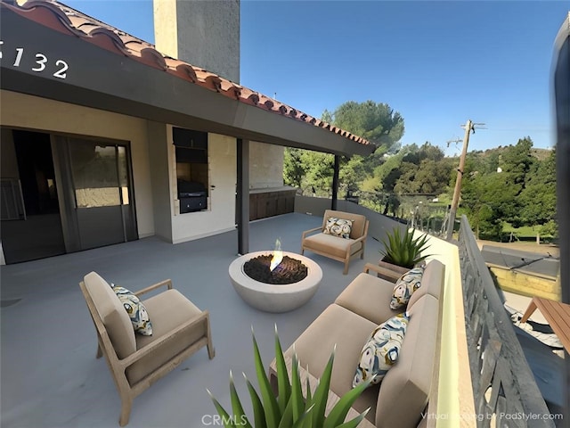 view of patio with an outdoor living space with a fire pit and a balcony