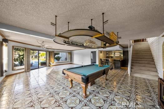 recreation room with pool table, ceiling fan, and a textured ceiling