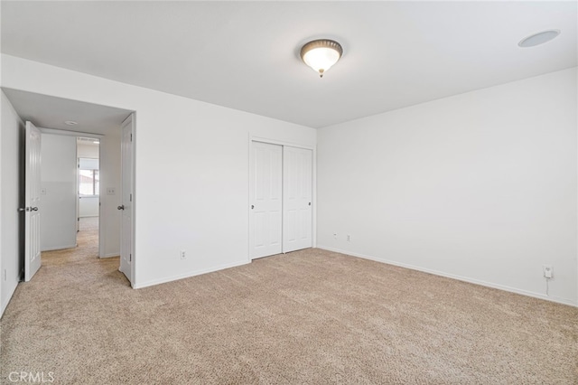 unfurnished bedroom featuring light carpet and a closet