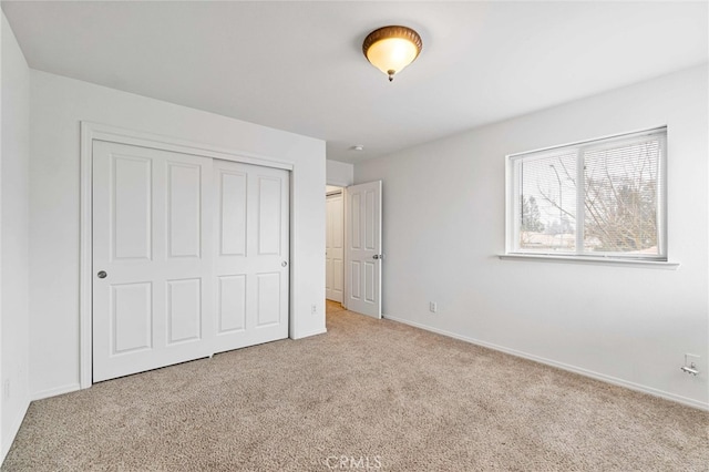 unfurnished bedroom featuring light colored carpet and a closet