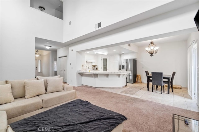 tiled living room featuring sink, a towering ceiling, and an inviting chandelier