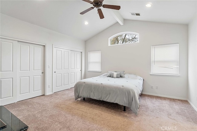 carpeted bedroom featuring multiple closets, ceiling fan, and lofted ceiling with beams