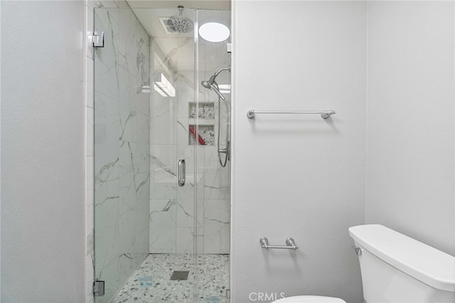 bathroom featuring toilet and a shower with shower door