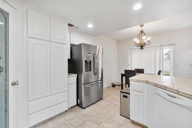 kitchen with white cabinets, dishwasher, hanging light fixtures, stainless steel fridge, and tile countertops