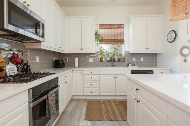 kitchen featuring stainless steel appliances, white cabinets, sink, and light wood-type flooring