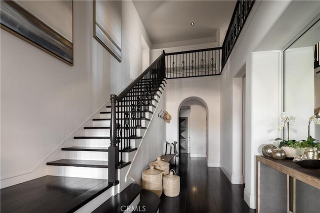 stairway with a high ceiling and wood-type flooring