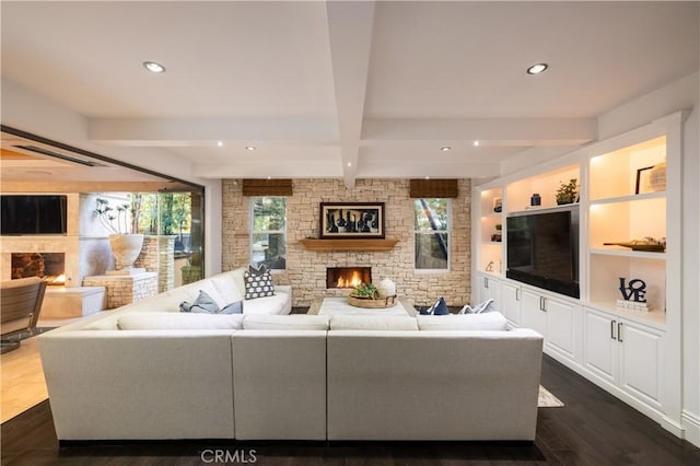 living room featuring beam ceiling, a stone fireplace, and dark hardwood / wood-style floors