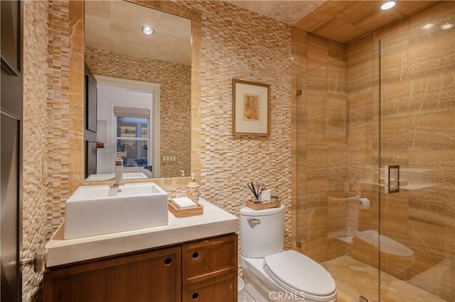 bathroom featuring a shower with door, vanity, and toilet