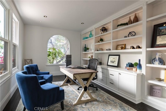 home office with built in features and dark hardwood / wood-style floors