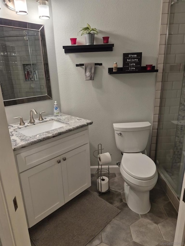 bathroom with a shower with shower door, toilet, and vanity