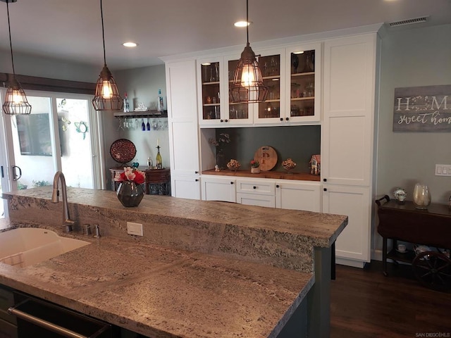 bar with white cabinetry, sink, hanging light fixtures, and light stone countertops