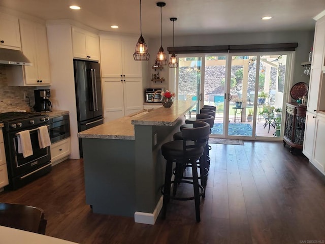 kitchen featuring white cabinets, black appliances, a center island, decorative light fixtures, and light stone counters