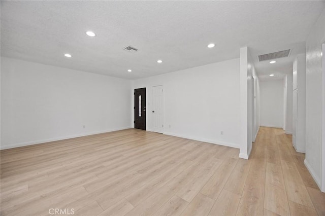 empty room with light wood-type flooring and a textured ceiling