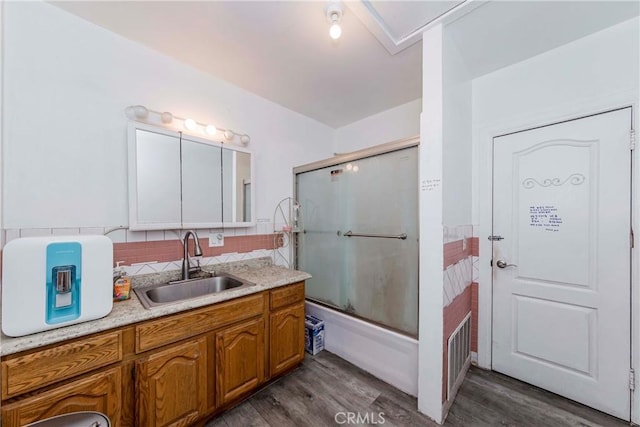 bathroom featuring vanity, shower / bath combination with glass door, tasteful backsplash, and hardwood / wood-style flooring