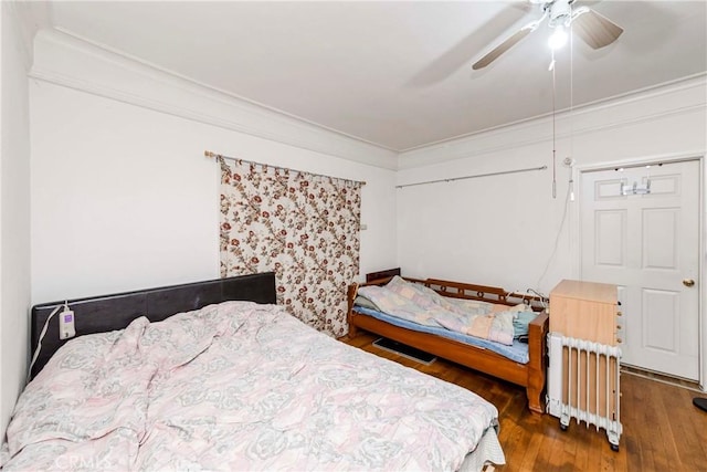 bedroom featuring ceiling fan, radiator heating unit, crown molding, and wood-type flooring