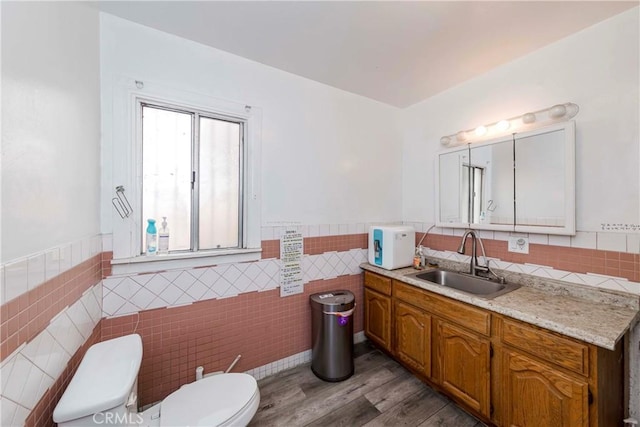 bathroom featuring tile walls, hardwood / wood-style floors, vanity, and toilet