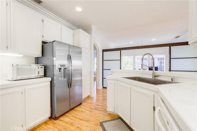 kitchen with light hardwood / wood-style floors, sink, white appliances, ornamental molding, and white cabinets