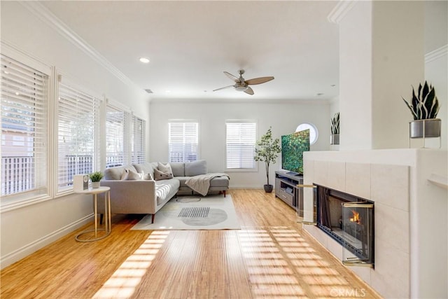 living room with ceiling fan, a fireplace, ornamental molding, and hardwood / wood-style flooring