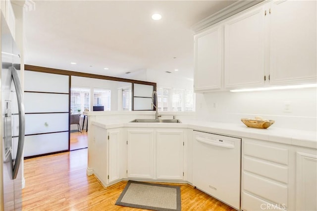 kitchen with white cabinets, dishwasher, sink, stainless steel refrigerator, and light wood-type flooring