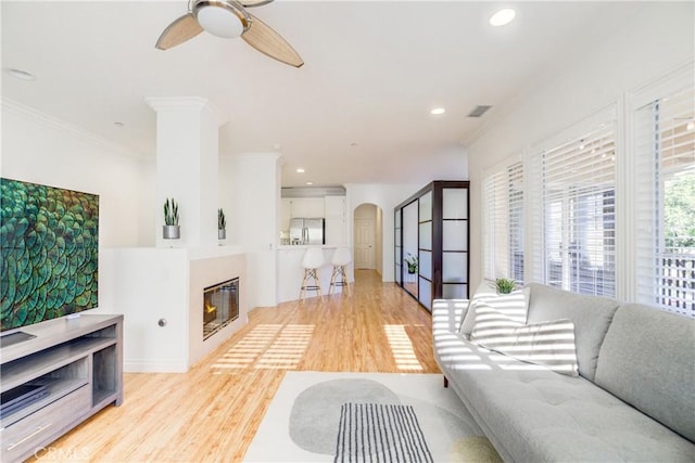 living room featuring ceiling fan, ornamental molding, and light hardwood / wood-style floors