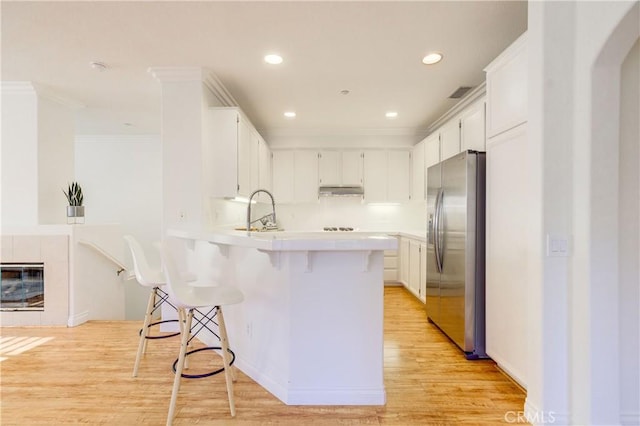 kitchen featuring stainless steel fridge with ice dispenser, white cabinetry, a kitchen bar, and sink