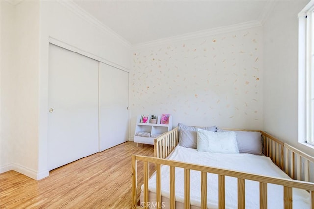 bedroom with a closet, ornamental molding, and hardwood / wood-style floors