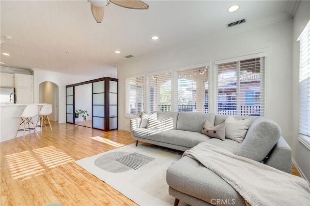 living room with ceiling fan, ornamental molding, light hardwood / wood-style flooring, and sink