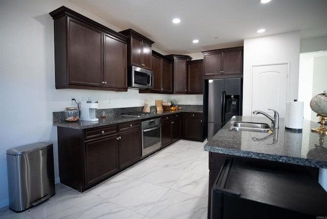 kitchen with dark stone counters, appliances with stainless steel finishes, dark brown cabinetry, and sink