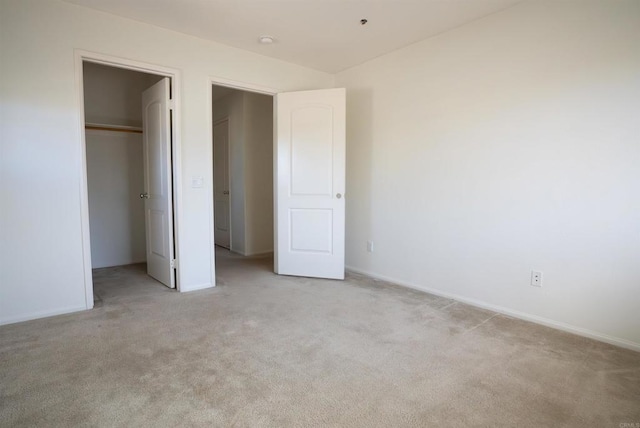 unfurnished bedroom featuring a closet, light carpet, and a spacious closet