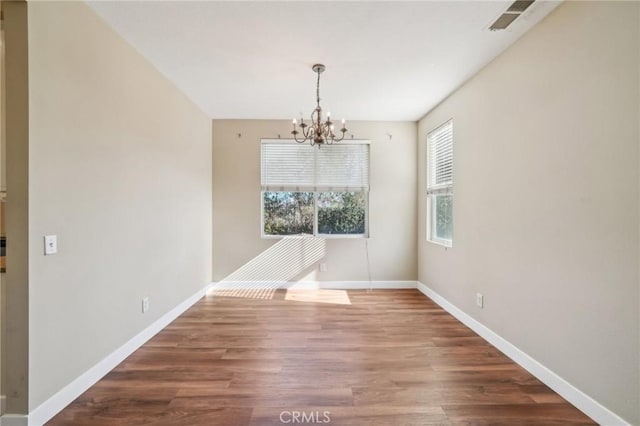 unfurnished dining area featuring wood-type flooring and a chandelier