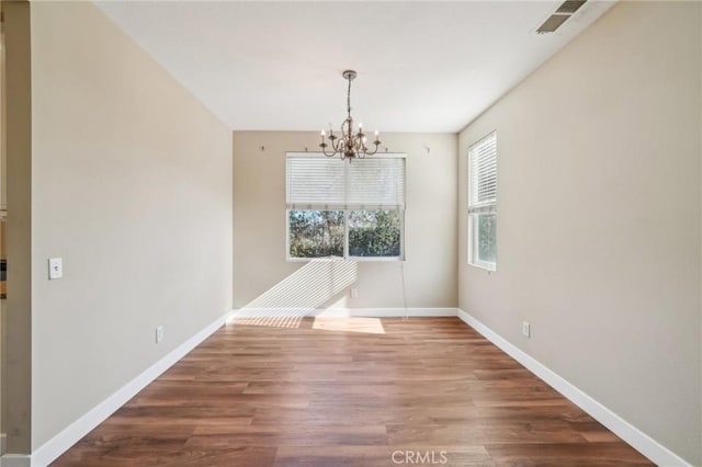 unfurnished dining area featuring an inviting chandelier and wood-type flooring