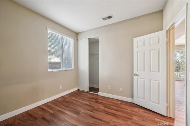 unfurnished bedroom with a closet, wood-type flooring, and multiple windows