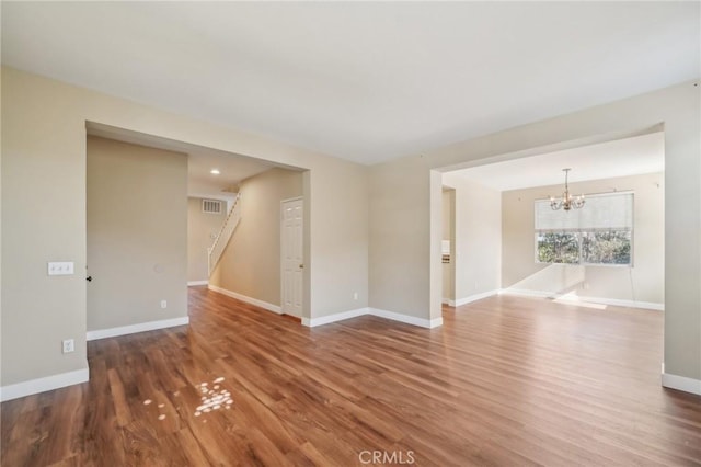 unfurnished room with hardwood / wood-style flooring and an inviting chandelier