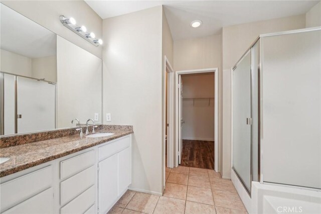 bathroom featuring tile patterned flooring, a shower with shower door, and vanity