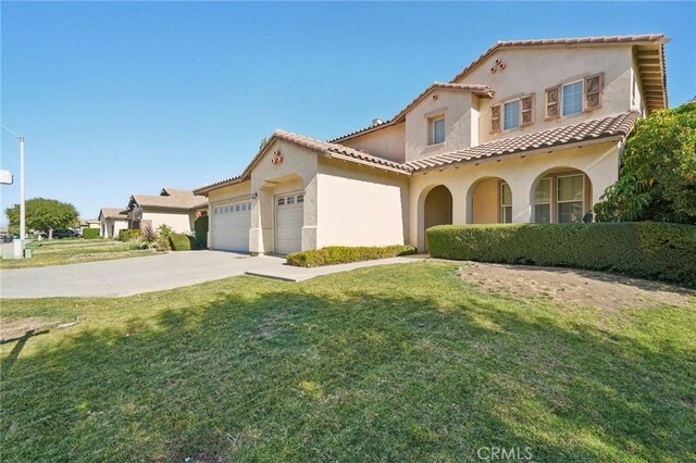 mediterranean / spanish-style home featuring a front yard and a garage