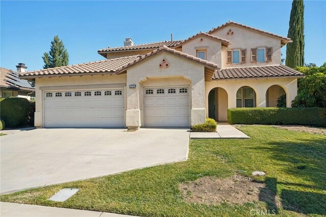 mediterranean / spanish-style home featuring a garage and a front lawn