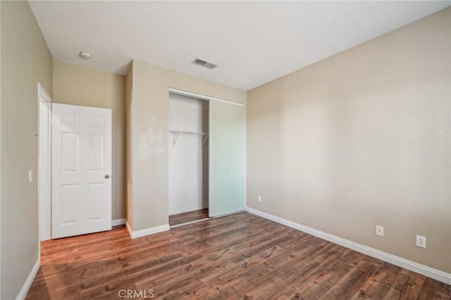 unfurnished bedroom featuring dark hardwood / wood-style flooring and a closet