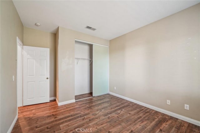 unfurnished bedroom featuring dark wood-type flooring and a closet